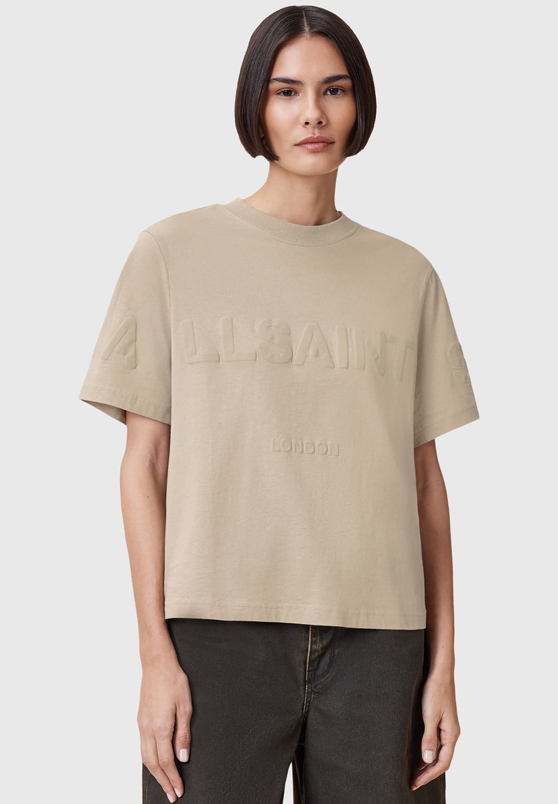 T-shirt in cotone beige con testo in rilievo "ALLSAINTS" e "LONDON" sul davanti, caratterizzato da una vestibilità comoda e maniche corte, design minimalista.