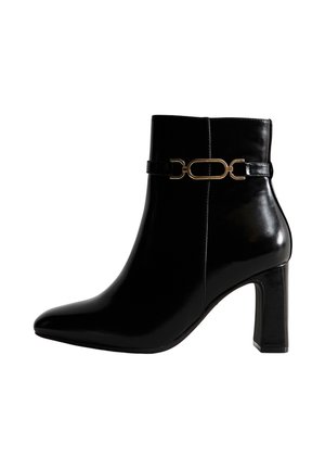 Schwarze Leder-Stiefelette mit spitzem Zehenbereich, vertikalen Nahtdetails und goldener Kettenakzent um den Knöchel. Design mit Stiletto-Absatz.
