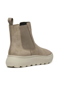 Bottines en suède beige avec une semelle rembourrée, des panneaux latéraux élastiques et une languette à l'arrière pour un enfilage facile.
