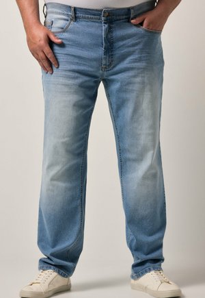 Jeans de mezclilla azul claro con un corte recto, que presentan un diseño desteñido, cierre de botón, lazos para el cinturón y bolsillos laterales. Combinados con zapatillas blancas.