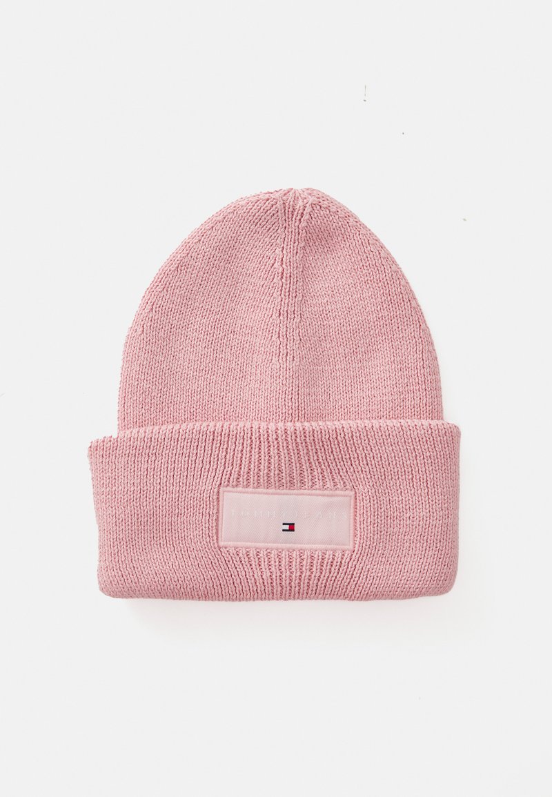Bonnet en tricot rose avec un revers et une étiquette rectangulaire en patch avec des lettres blanches et un petit emblème coloré.