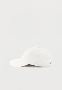 Gorra de béisbol blanca de algodón que presenta una visera curva, ojales cosidos en la corona y una correa ajustable en la parte trasera.