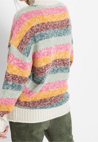 Suéter de punto con rayas multicolores en rosa, amarillo, marrón y verde. Puños y dobladillo acanalados con un ajuste holgado y oversize.