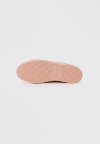 Suola di scarpa in gomma rosa con un battistrada decorato, texture liscia e marchio in rilievo. Progettata per aderenza e durabilità.