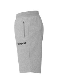 Grijze shorts van zacht materiaal, met een ritszak aan de zijkant en een zwart "uhlsport" logo op het onderbeen.