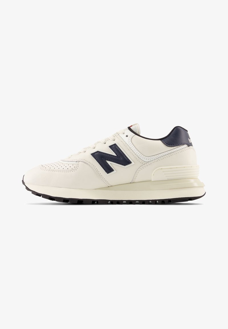 Weißer Ledersneaker mit marineblauen Akzenten, durchlöchertem Design an der Zehe und einer strukturierten, dunklen Gummisohle. Enthält ein auffälliges "N"-Logo.