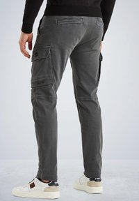 Graue Cargo-Hosen mit mehreren Seitentaschen, schmalem Schnitt und genähten Details, kombiniert mit weißen Sneakers mit schwarzen Akzenten.