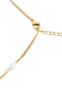 Náhrdelník zo zlatého reťaze s lobster sponou, uprostred reťaze sa nachádza oválny biely korálik. Dizajn so štruktúrovanými článkami.