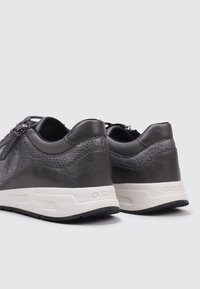 Sneaker in pelle nera con dettagli testurizzati e suola bianca. Presentano un design a taglio basso e un logo discreto sul tallone.