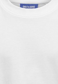 Camiseta blanca de cuello redondo hecha de algodón, con una etiqueta azul que muestra el texto "ONLY & SONS NEXT GENERATION" en blanco. Textura suave.