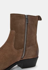 Ruske nubuk ankle botit, jossa on sivuvetoketju, musta korko ja sileä pinta. Suunnittelussa on vetoketju, joka helpottaa käyttöä.