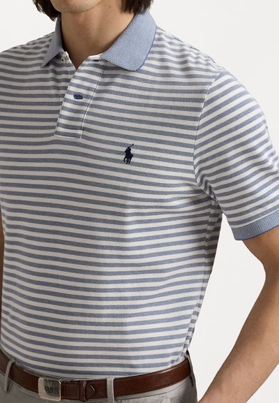 Polo w paski z krótkim rękawem w biało-granatowe kolory, z jednolitą niebieską kołnierzykiem oraz małym haftowanym logotypem na piersi.