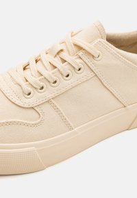 Beige kangastossud ümmarguste varvastega, kuue silmaga, lamedate paeltega ja kummitaldaga. Struktuurne pind tõstetud detailidega.