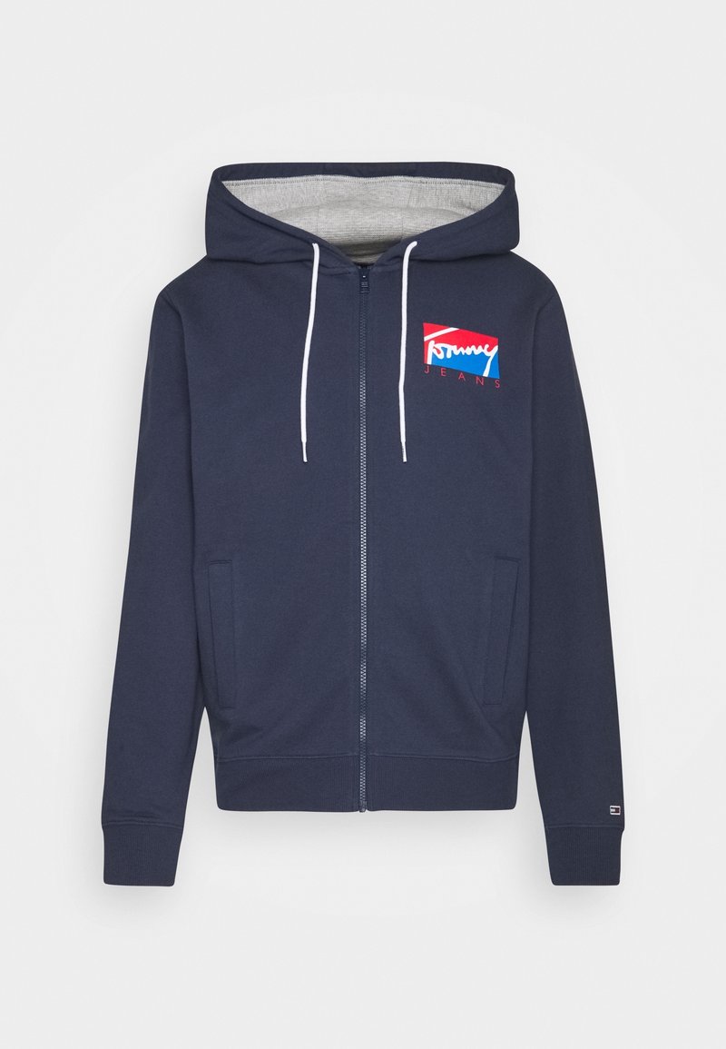 Marineblaue Zip-Hoodie mit einer Kordelzugkapuze, die ein graues Innenfutter und ein rot-weiß-blaues Logo auf der linken Brust zeigt.
