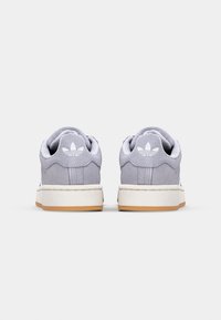 Light grey suede sneakers with white branding on the heel, white midsole, and gum rubber outsole. Low-top, round-toe design.