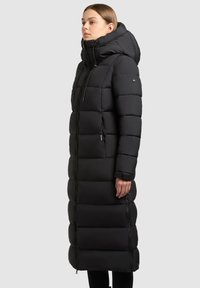 Lång svart puffjacka med huva, vertikalt sydd design, frontdragkedja, sidofickor och en skräddarsydd passform.
