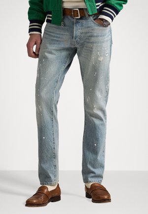 Lichtgewassen denim jeans met een relaxte pasvorm, voorzien van versleten details en verfsplatsingen. Gepaard met bruin leren loafers.