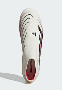 Vit fotbollssko med en texturerad ovandel, svarta och rosa accenter samt tre svarta ränder på sidan. Har en snörningsfri design.