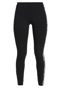 Svarta leggings med en åtsittande design, som har ett texturerat vitt mönster längs sidorna och en slät, elastisk tygkonstruktion.