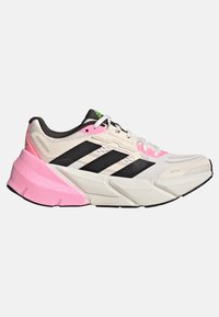 Baskets de sport avec une tige beige, des rayures noires, une semelle intermédiaire rose et une semelle texturée. Présente un avant lacé et des éléments de design superposés.