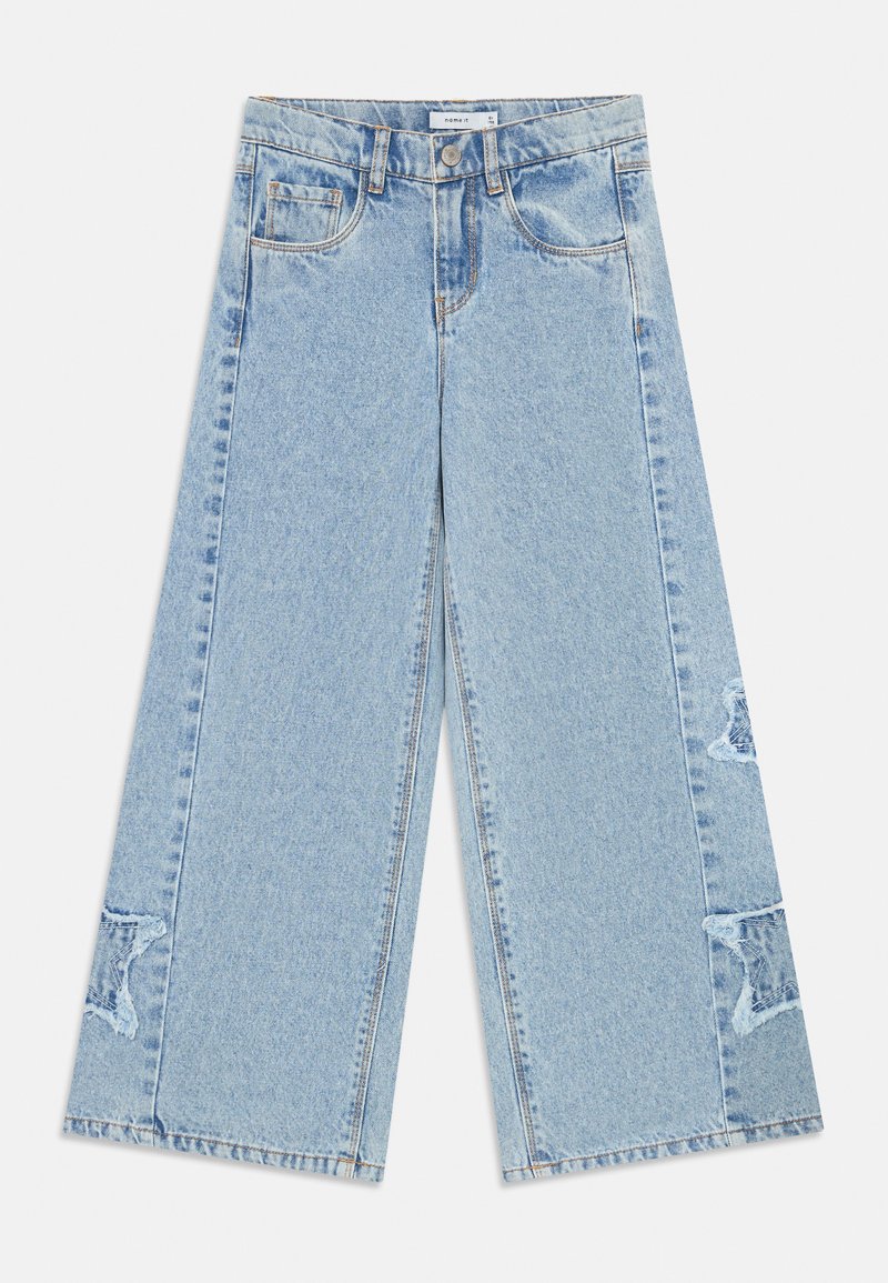 Gaiši zili, platās kājas džinsi, izgatavoti no denima, ar divām priekšējām kabatām un nolietotām akcentēm uz kājām. Tīrs, taisns griezums un minimāla šūšana.