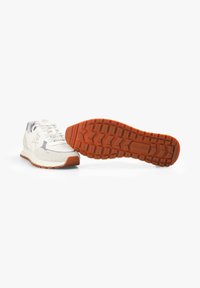 Zapatillas deportivas de color gris claro con una superposición de ante, suela de goma naranja y patrón de banda de rodadura texturizada. Cuenta con cierre de cordones y detalle de logo.