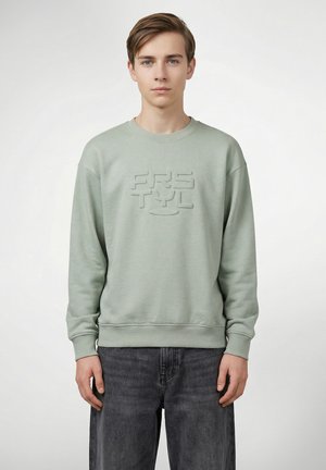 Lysegrøn sweatshirt med et tekstureret, præget logo på fronten. Klassisk rund hals, ribkanter ved ærmer og kant samt mørke jeans.