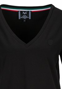 Zwarte V-hals shirt van gladde stof. Heeft een klein, reliëflogo op de linkerbovenborst en een meerkleurige gestreepte halsafwerking. Maat S.