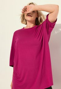 Fuchsia oversized t-shirt met een ronde halslijn en korte mouwen, gemaakt van zachte stof met een gladde textuur.