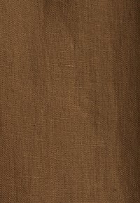 Tissu marron tissé avec une texture grossière et des fils entrelacés visibles créant un motif en grille.