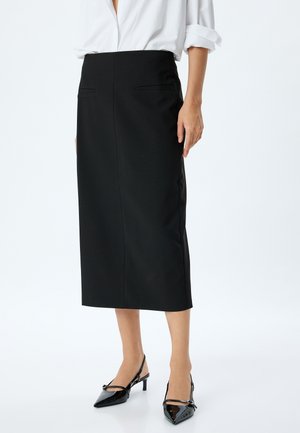 Schwarzer Midirock mit tailliertem Bund, zwei Gesäßtaschen und glatter Textur, kombiniert mit spitzen schwarzen Slingback-Schuhen.
