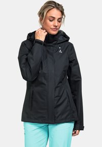 Schwarze wasserdichte Jacke mit Kapuze, Reißverschluss hinten und zwei Seitentaschen. Sie hat eine glatte Textur und ein kleines Logo auf der Brust.