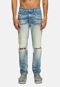 Light blue distressed jeans with ripped knees, five-pocket design, and fading details. Fabric appears denim with a worn texture.