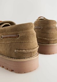 Braune Wildlederschuhe mit runder Spitze, geschichtetem Design, Gummisohle, kontrastierendem Nähen und Lederdetails in der Nähe der Schnürsenkel.