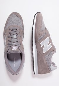 Szare zamszowe i tekstylne sneakersy z siateczkowymi panelami, z białym logo "N", okrągłym noskiem i czarną gumową podeszwą.