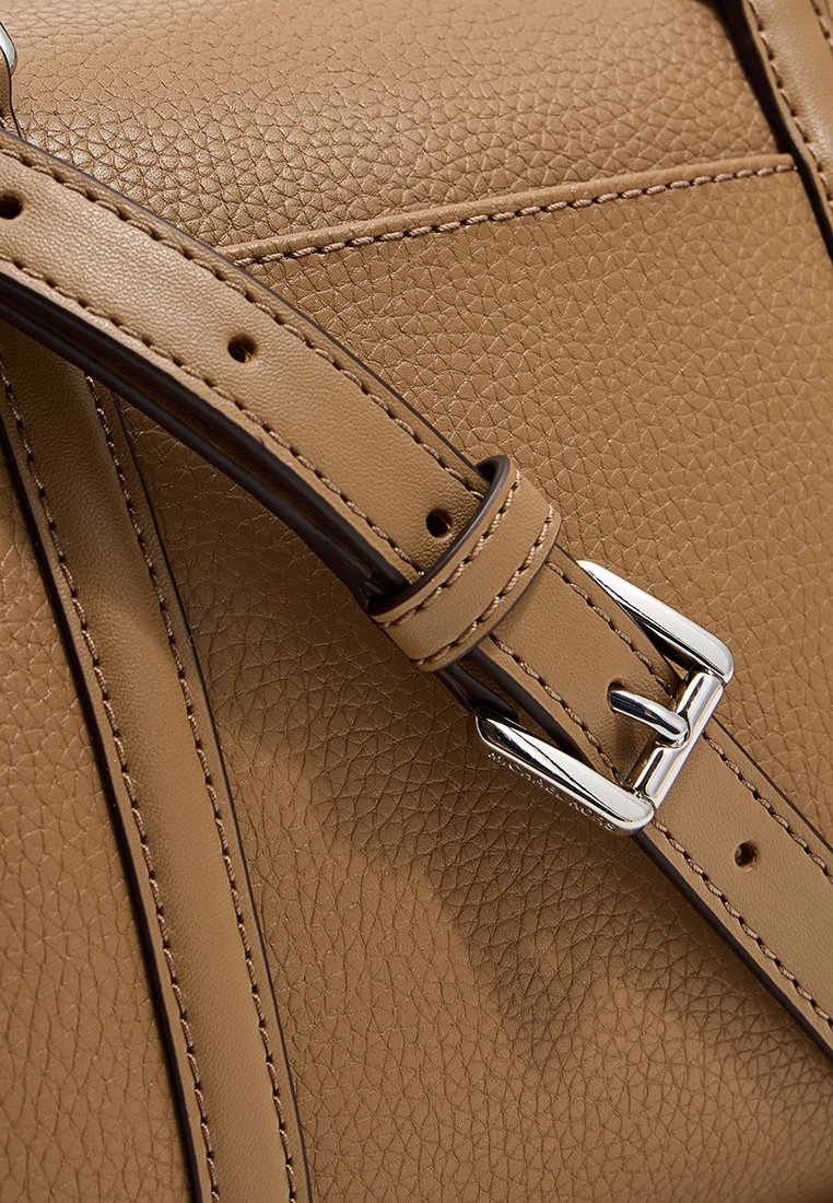 Sangle de sac en cuir tan avec finition texturée, dotée d'une boucle en argent et d'accents cousus, mettant en valeur sa construction durable.