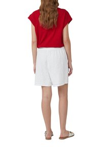 Rode shirt met korte mouwen, gepaard met witte shorts van oogjes. De shorts hebben een verzamelde elastische tailleband en delicate geborduurde patronen.