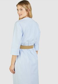 Helles blau gestreiftes Kleid mit drei Viertelärmeln, tailliert mit einem gewebten, hellbraunen Gürtel, mit einem lässigen, lockeren Schnitt.