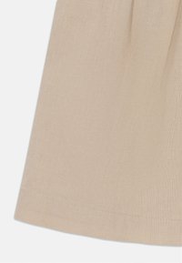 Beige linnendoek met een gladde textuur, voorzien van een gezoomde rand en lichte plooien aan de bovenkant. Geschikt voor lichte kleding.