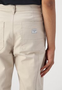 Beige werkbroek gemaakt van stevig katoen twill, met een label op de achterzak en een nette, gestructureerde uitstraling.