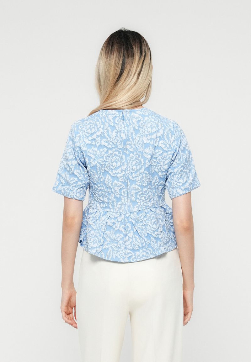 Bluse mit blauem Blumenmuster, kurzen Ärmeln, tailliertem Schnitt und Peplum-Design. Leichter Stoff mit strukturierten Stickdetails.