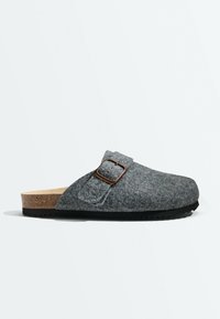 Sabot en feutre gris à enfiler avec semelle intérieure en liège, semelle noire, et une bride marron ajustable avec boucle sur le côté.