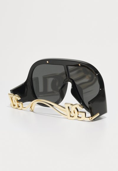 Schwarze übergroße Sonnenbrille mit glänzender Oberfläche, ausgestattet mit einem goldenen Metallakzent und Logo an der Seite, unverwechselbares Wellendesign.