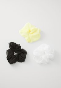 Tre scrunchie trasparenti: una nera, una bianca e una gialla pastello, tutte con una texture morbida e un design arricciato, esposte su uno sfondo bianco.