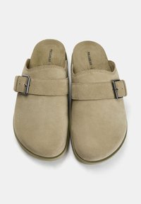 Beige suède instap schoenen met een brede band en metalen gesp. Lichte, gestructureerde oppervlakte en gevormd zoolontwerp.