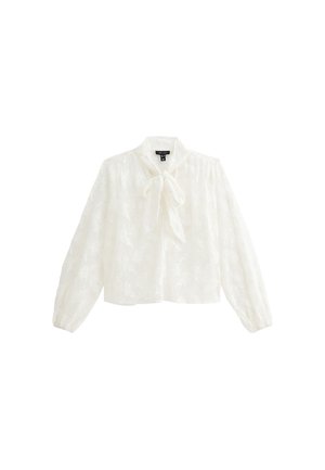 Blusa blanca con cuello y detalle de lazo. Mangas largas y abullonadas con puños elásticos. Tejido texturizado con sutil patrón floral. Diseño corto.