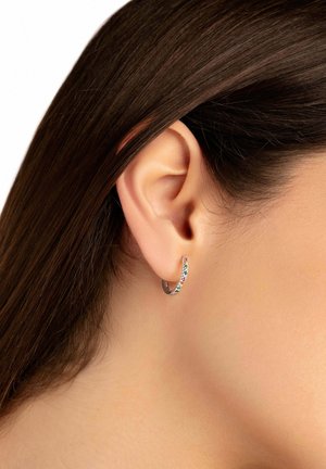 Pendiente de aro plateado adornado con piedras preciosas multicolores. Diseño ligero con forma curva, descansando contra el lóbulo de la oreja.