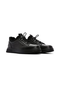 Black leather sneakers with a textured upper, lace-up closure, and rubber sole featuring a zigzag pattern along the edge.