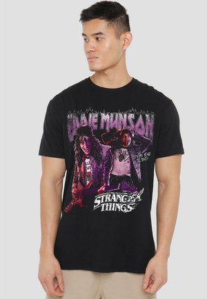 Black cotton graphic t-shirt featuring "Eddie Munson" and "Stranger Things" in bold, colorful print with a rock-themed design.