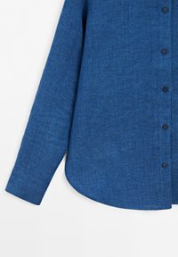 Long-sleeve blue linen shirt sleeve and side with black buttons on a white background.